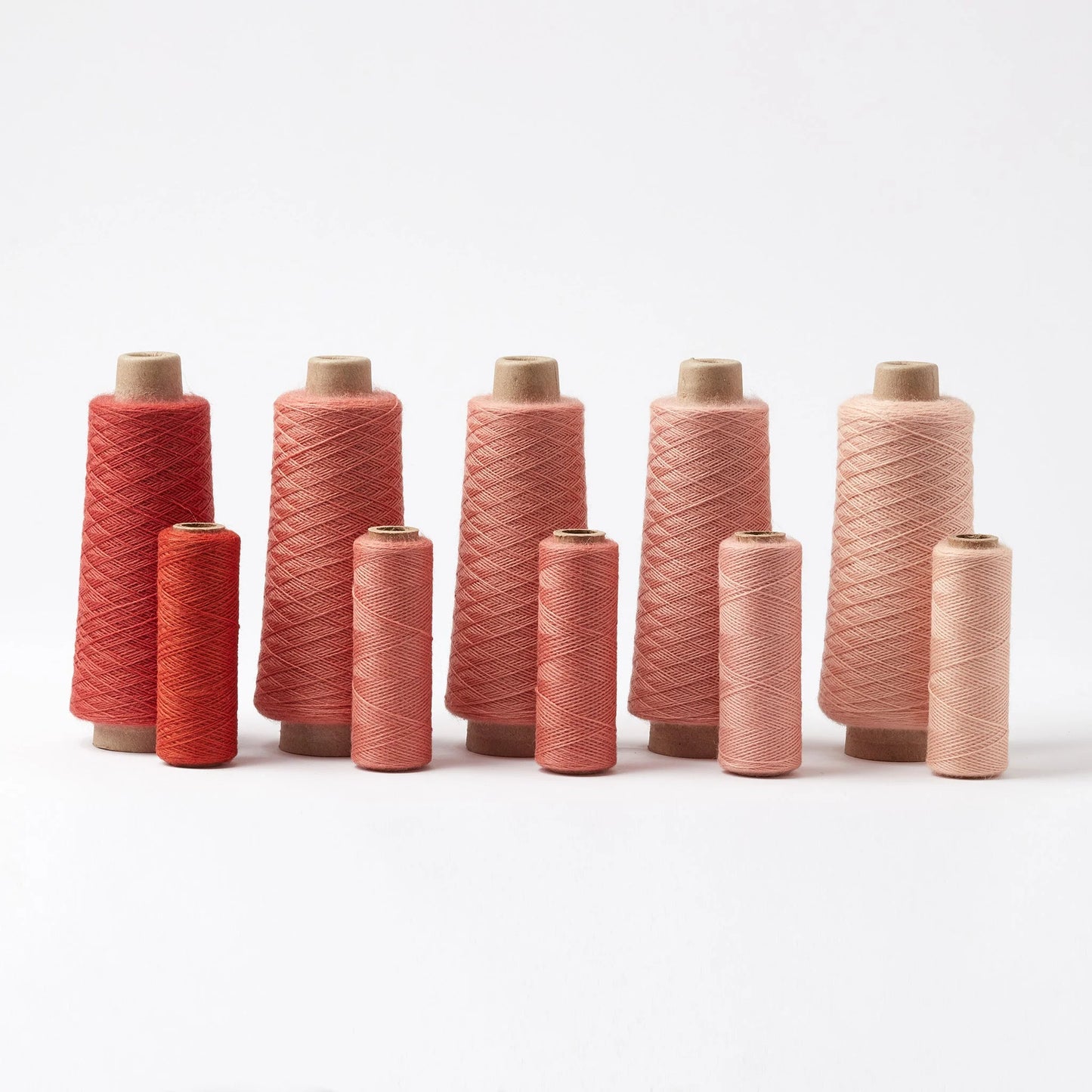Set of pink and red spools of thread on a white background