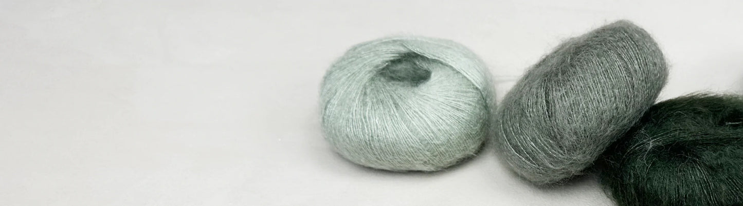 Three skeins of yarn in light green, gray, and dark green on a white background