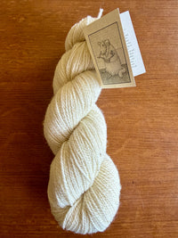White skein of yarn with a label on a wooden surface