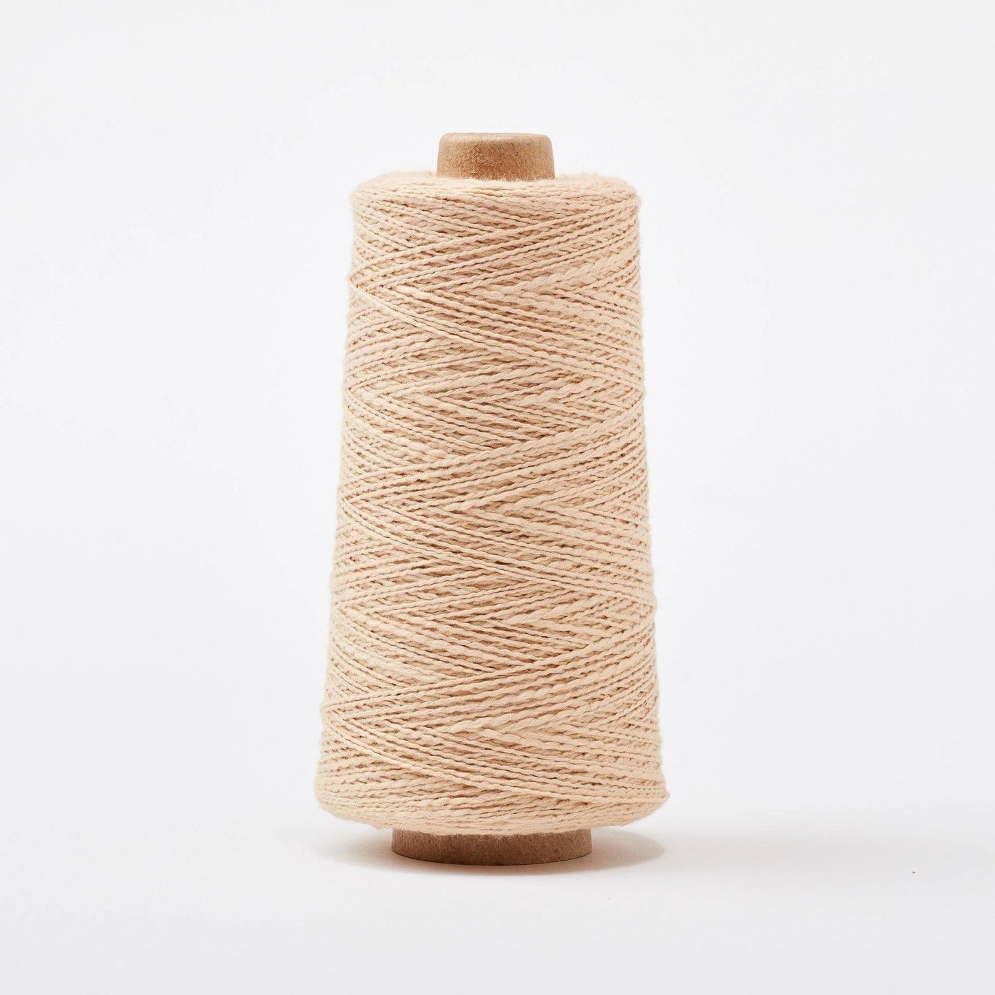 Spool of beige yarn on a white background