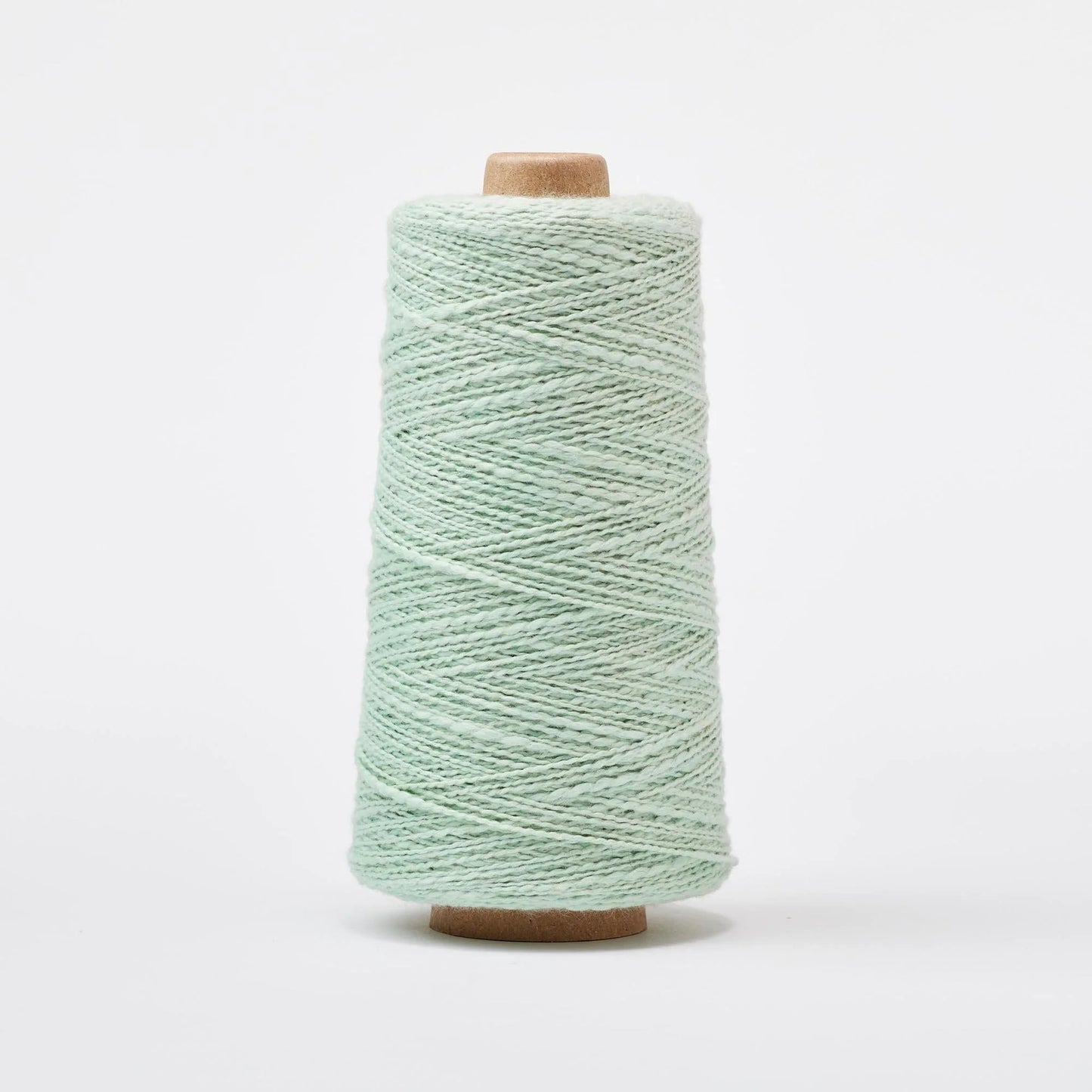 Spool of light green yarn on a white background