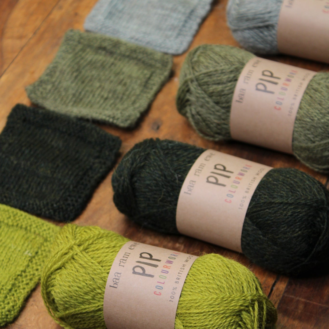 Bundles of green yarn with visible labels on a wooden surface